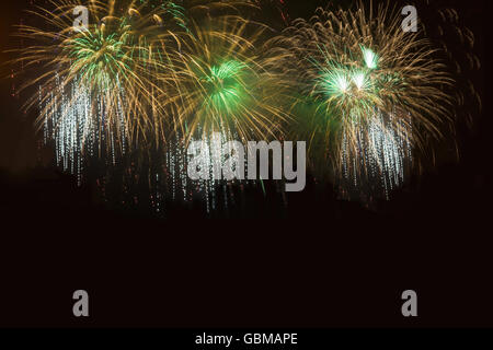 Golden and green fireworks over night sky. Celebration colorful fireworks. Holidays salute of various colors on night sky. Stock Photo