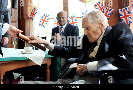 Actress Charlotte Rampling, presents her father Godfrey Rampling with a commemorative baton after becoming Britain's oldest Olympian as he celebrates his 100th Birthday during a party at Bushey House, Bushey. Stock Photo