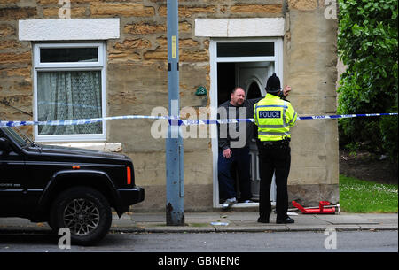 A neighbour talks to police at the scene in Shildon, County Durham where a man was shot last night. Stock Photo