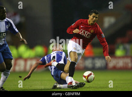 Manchester United's Cristiano Ronaldo (right) goes down under a challenge from Wigan Athletic's Lee Cattermole during the Barclays Premier League match at the JJB Stadium, Wigan. Stock Photo