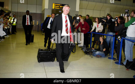 Manchester United manager Sir Alex Ferguson arrives back at Manchester Airport, Manchester. Stock Photo