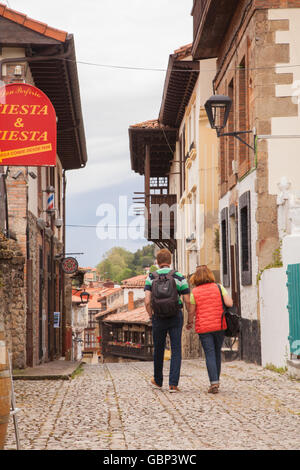 Man and woman walking down a cobbled street in the seaside resort  Comillas Northern Spain Stock Photo