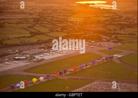 Hot air balloons line up on the main runway at Bristol International Airport at sunrise, as they prepare to fly from the airport for the first time. Stock Photo