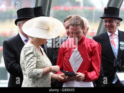 Jockey Richard Hughes (right) is presented a trophy by Camilla, Duchess of Cornwall (left) after winning the Queen Anne Stakes at Ascot on Paco boy Stock Photo