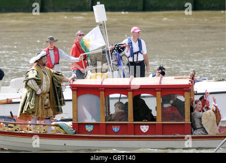 A man and woman dressed as King Henry VIII and his queen sail up the river Thames on the Royal Shallop Jubilant, accompanied by an entourage of Tudor courtiers and musicians, London. Stock Photo