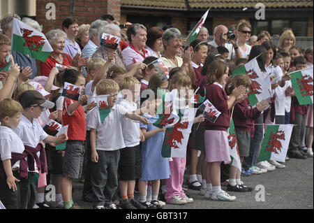 Children from Ysgol Rhys Pritchard Primary school wave flags as they await the arrival of The Royal Highness' The Duchess of Cornwall and The Prince Of Wales at Llandovery Hospital, Dyfed, Wales. Stock Photo