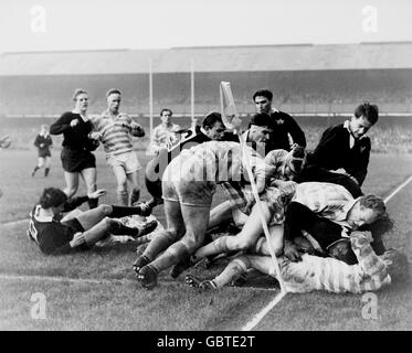 Oxford University's John Coker (dark shirt, on floor, r), the first black African to win a blue, is bundled into touch just short of the line Stock Photo