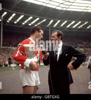 Manchester United captain Noel Cantwell (l) hangs onto the FA Cup as he is interviewed by David Coleman (r) after his team's 3-1 win Stock Photo