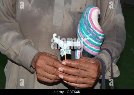 Traditional candy seller (gattay wala) holding the delicious pakistani chew rainbow candy (gatta) Stock Photo