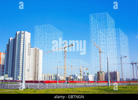 Block of flats under construction, working cranes and wire-frame structures of future buildings, photo collage Stock Photo