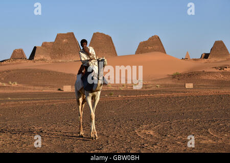 Africa, Sudan, Nubia, nomad with dromedary, Pyramids of Meroe in background Stock Photo