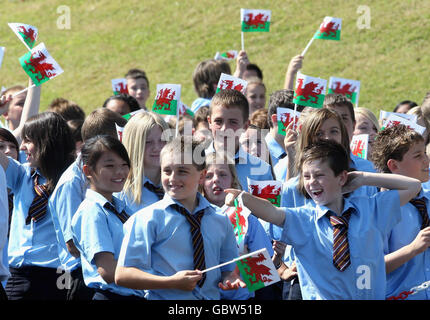 Children wave Welsh Flags as Prince Charles, Prince of Wales, makes a speech during a visit to Treorchy Comprehensive School. in Wales. Stock Photo