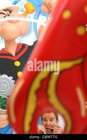 American artist Jeff Koons is seen through the claw of his work 'Acrobat, 2003-2009' as he speaks at a press conference at an exhibition of work from his 'Popeye' series, at the Serpentine Gallery, London. Stock Photo