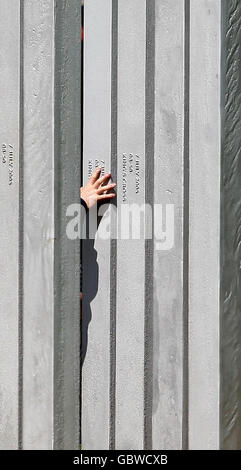 A visitor touches a pillar at the memorial to the victims of the 7th July 2005 terrorist attacks on London, in Hyde Park, London. Stock Photo