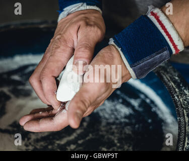 Preparing hands with chalk before beginning calisthenics, gymnastics fitness training. Stock Photo