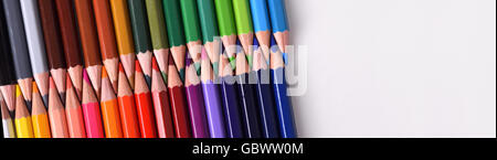 Background colored pencils lined up palette with tips facing each aligned diagonally on white table. Top and panoramic view. Stock Photo