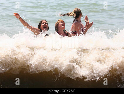 Three friends (names not given) enjoy the surf of Brighton beach in Brighton, East Sussex, as the warm weather continues. Stock Photo