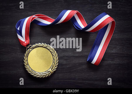 Gold medal on black wood background with blank face for text, concept for winning or success Stock Photo
