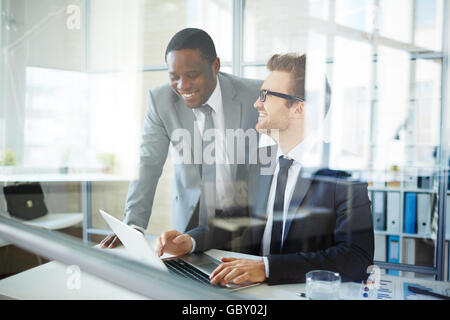 Two colleagues using computer together at office Stock Photo