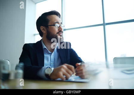 Pensive businessman looking in the office window Stock Photo