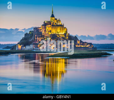 Classic view of famous Le Mont Saint-Michel tidal island in beautiful twilight during blue hour at dusk, Normandy, France