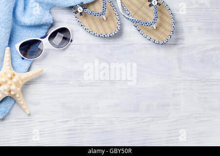 Beach accessories. Towel, flip-flops, starfish and sunglasses on wooden background. Top view with copy space Stock Photo