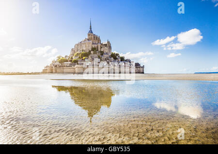 Classic view of famous Le Mont Saint-Michel tidal island on a sunny day with blue sky and clouds, Normandy, northern France