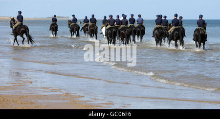 Soldiers from the Blues and Royals of the Household Cavalry Mounted Regiment exercises their horses on Holkham Beach, in Holkham, Norfolk during their three week summer training camp and a break from ceremonial duties. Stock Photo