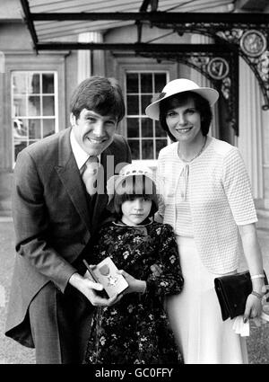 Emlyn Hughes shows off his OBE with his wife Barbara and daughter Emma after his investiture at Buckingham Palace Stock Photo