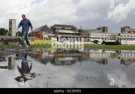 Groundstaff work on the pitch at Old Trafford as Lancashires Mal Loye heads to the Indoor Cricket centre during the Twenty20 Cup Quarter Final match at Old Trafford Cricket Ground, Manchester. Stock Photo