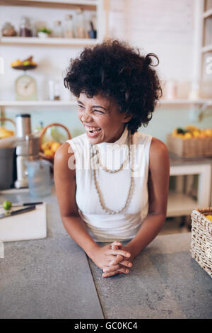 Portrait of cheerful young female standing behind counter. Successful juice bar owner looking away and smiling. Stock Photo