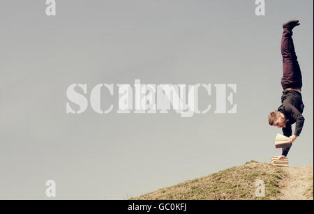 SCIENCE word - Guy standing on his head and reading Stock Photo