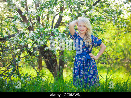 Adorable kid playing in nature. Cute little child, blonde toddler girl playing in blooming cherry garden on beautiful spring or summer day Stock Photo