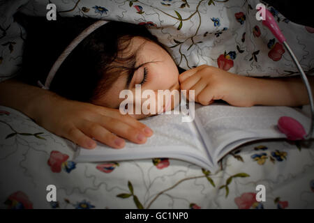 Little girl sleeping in the bed after reading Stock Photo