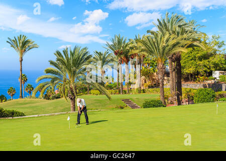 Unidentified man playing on golf course in tropical landscape of Tenerife, Canary Islands, Spain Stock Photo