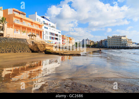 Reflection of El Medano town buildings in water on beach at sunrise, Tenerife, Canary Islands, Spain Stock Photo