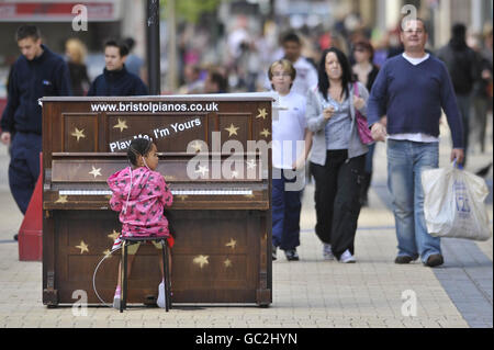 4-year-old Ashanti James from fishponds plays a solitary piano in the centre of Broadmead, Bristol's main shopping area, which is part of an art installation titled 'Play Me' by Bristol artist Luke Jerram. Stock Photo