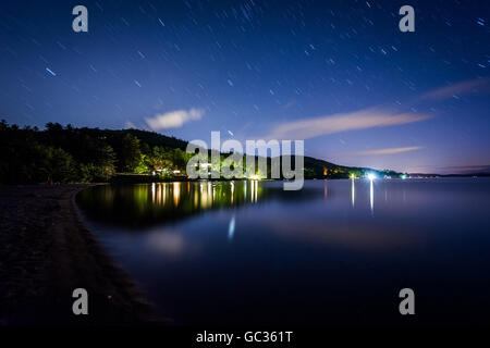 Long exposure of stars moving over Lake Winnipesaukee at night, at Ellacoya State Park, in Laconia, New Hampshire. Stock Photo