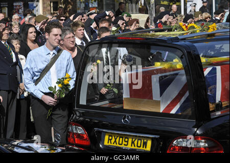 A man makes his way towards the rear of the hearse to lay flowers for Acting Serjeant Stuart McGrath, from 2nd Battalion The Rifles during his repatriation as the funeral procession moves through Wootton Bassett. Stock Photo