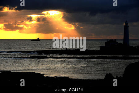 The sun rises over St Mary's Lighthouse in Northumberland. Stock Photo