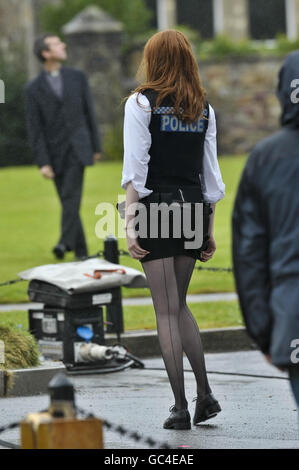 Doctor Who's assistant, actress Karen Gillan, dressed as a police officer, pulls her short skirt down during filming on set near the cathedral in Llandaff, Cardiff, Wales, where the latest series of Doctor Who is being filmed. Stock Photo