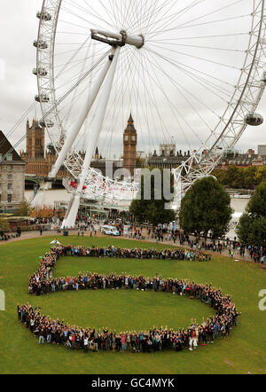 An aerial view of hundreds of climate change demonstrators led by 350 ambassador Bianca Jagger forming a human figure five as part of the Big 5 for 350 global day of climate action, in Jubilee Gardens on London's South Bank. Stock Photo