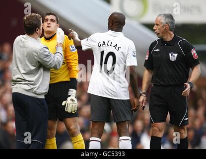 Arsenal goalkeeper Vito Mannone (2nd left) receives treatment for an injury as team mate William Gallas (2nd right) points out to referee Chris Foy (right) Stock Photo