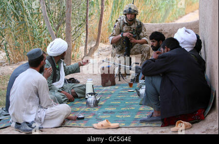 Platoon commander Lieutenant Ben Rutt, 28, from Cumnor, Oxford, of the Coldstream Guards speaks with Afghans whilst on a foot patrol in an area west of Lashkar Gah near to Patrol Base Bolan, Afghanistan. Stock Photo