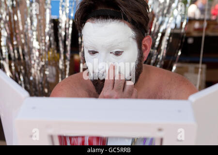 Man applying white base makeup on face - USA Stock Photo