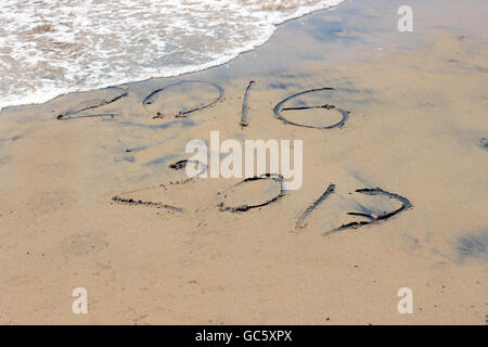 New Year 2017 is coming concept - inscription 2016 and 2017 on a beach sand, the wave is covering digits 2016. Stock Photo