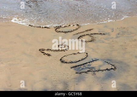 New Year 2017 is coming concept - inscription 2016 and 2017 on a beach sand, the wave is covering digits 2016. Stock Photo