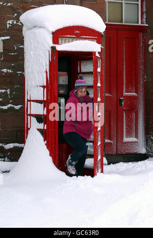 A woman uses a phone box in St Boswells in the Scottish Borders after a night of heavy snowfall. Stock Photo