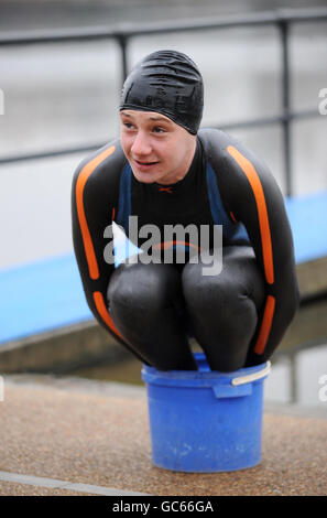 Triathlon world champion Great Britain's Alistair Brownlee warms his feet during the photocall at Serpentine Lake, London. Stock Photo