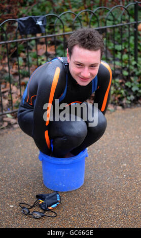 Triathlon world champion Great Britain's Alistair Brownlee warms his hands and feet during the photocall at Serpentine Lake, London. Stock Photo
